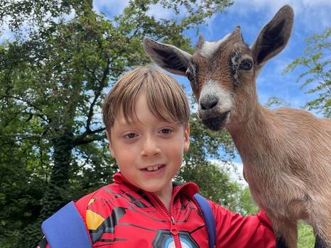 Eine junge Person und eine Ziege schauen nebeneinander Richtung Kamera. Eine junge Person und eine Ziege schauen nebeneinander Richtung Kamera.