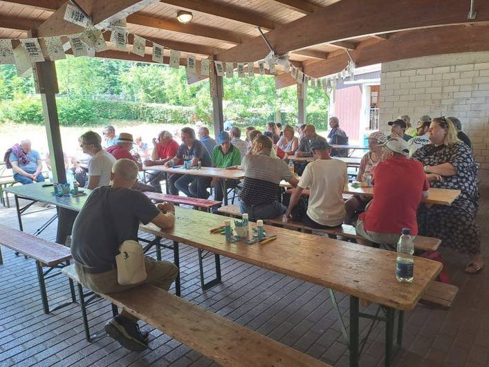 Sommerfest 2025 Begleitetes Wohnen in Familien (BWF) – Personen sitzen im Pavillon und im Freien davor. 